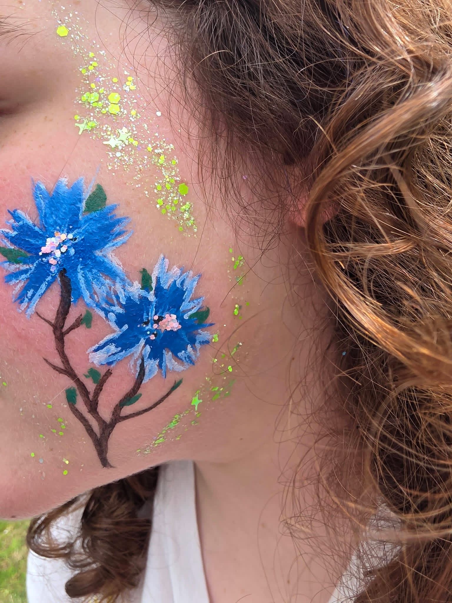 Blue flower face paint on a cheek