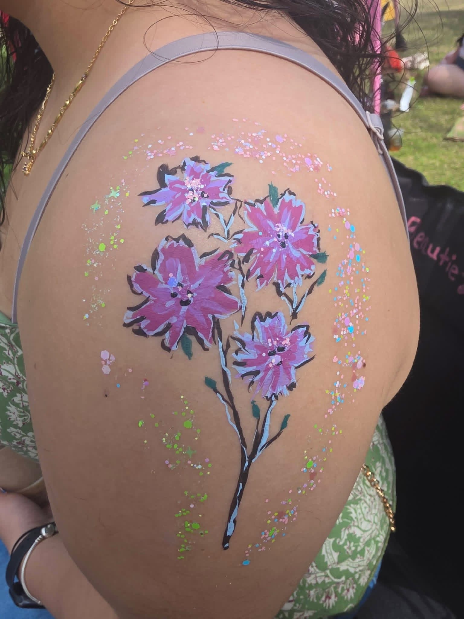 Purple flower body paint on a shoulder